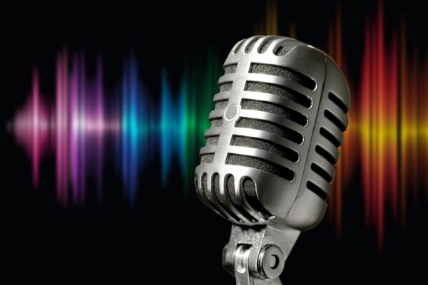 Grafika na kolorowym tle przedstawiająca mikrofon.
