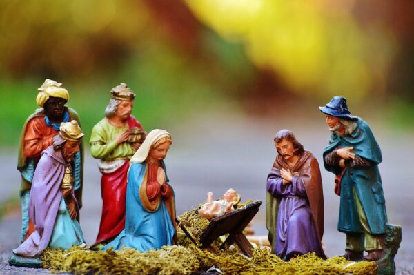 Szopka bożonarodzeniowa. Na kolorowym rozmytym tle od lewej postaci: król, król, król, MAryja, w żłóbku Dzieciątko Jezus, św. Józef i pasterz. Twarzami zwróceni na Dzieciatko Jezus. Maryja i Józef klęczą, pozostali stoją. Szaty są kolorowe.